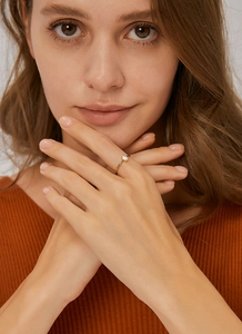 Primer plano de un anillo dorado con circonita rectangular en el dedo de una modelo