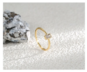 Primer plano de un anillo dorado con circonita cuadrada sobre una piedra moderna