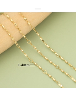 Detail einer 1,4mm goldbeschichteten Edelstahlkette mit gedrehten Wellengliedern auf Holz