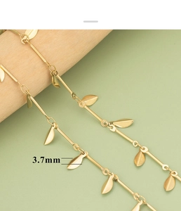 Makro-Detail einer goldenen Edelstahlkette mit 3,7 mm Blattanhängern auf Holz