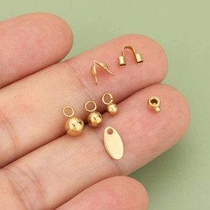 DIY stainless steel gold-plated jewelry making supplies set on a fingertip close-up