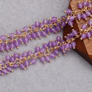 Macro detail of 18K gold-plated beaded tassel chain with translucent purple stones