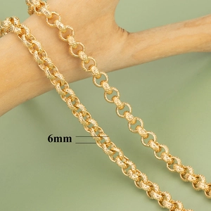 Detail einer 6mm 18K vergoldeten Rolo-Kette mit Rautenmuster auf einem Holzzweig