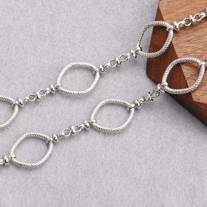 Close-up of textured silver oval links and smooth round rings for DIY jewelry chain making