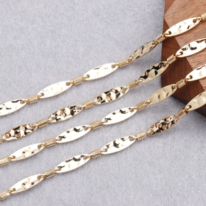 Macro shot of 18K gold plated oval hammered metal pieces and wire-wrapped chain detail