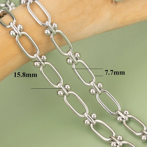 Detail of 18K gold plated silver paperclip chain with bead accents on wood branch