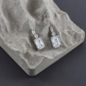 Macro shot of silver zircon rectangle earrings with pavé setting on grey rock
