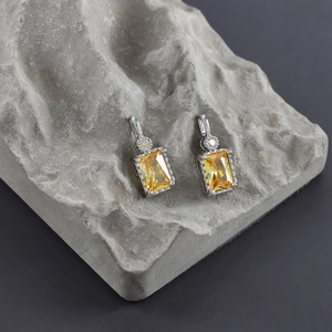 Macro shot of rectangular yellow zircon earrings with silver plated claw setting