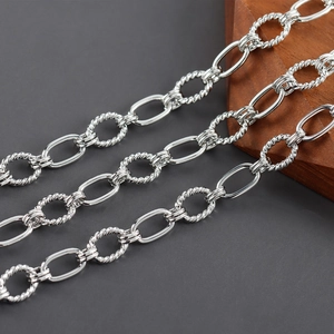 Detalle macro de cadena de plata rodiada con eslabones lisos y trenzados para joyería artesanal