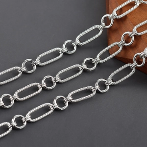 Detalle macro de cadena de eslabones en O bañada en plata con anillos trenzados y pulidos