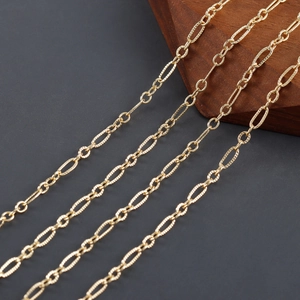 Makro-Detail einer 18k vergoldeten Figaro-Kette mit texturierten ovalen und glatten Gliedern