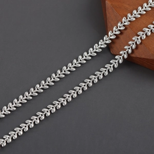 Macro shot of silver-plated leaf pattern jewelry chain on a rustic wooden display