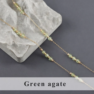 Detail of gold chain with translucent green agate square beads and golden spacers