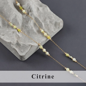 Detailed macro shot of stainless steel gold chain with faceted citrine gemstone beads