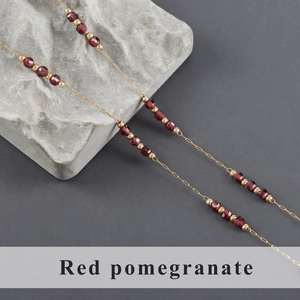 Detail of gold stainless steel chain with red garnet beads and golden accents