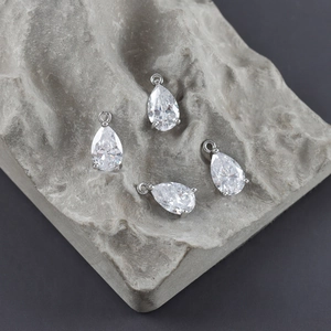Macro shot of silver-plated pear-cut zircon pendants with claw settings on a stone surface