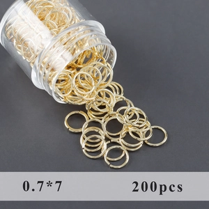 Λεπτομερής όψη χρυσών κρίκων 0,7x7mm που πέφτουν από ένα διαφανές πλαστικό μπουκάλι