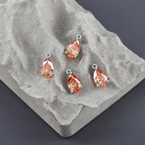 Macro detail of pear-shaped orange zircon pendants with silver prong setting and loop hooks