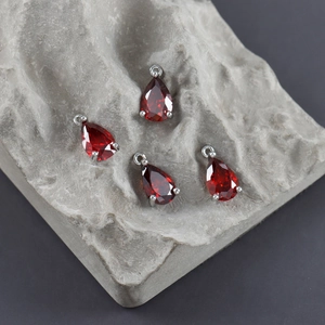 Macro shot of four red pear-shaped zircon pendants with silver claw settings and top loops