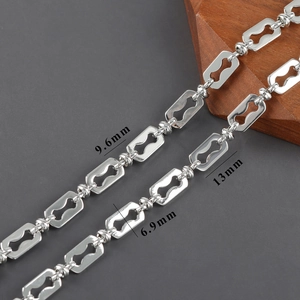 Détail macro d'une chaîne croisée en forme de 8 plaquée argent avec mesures de 9,6 mm de large