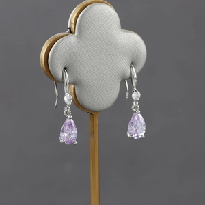 Elegant 18k gold plated drop earrings with purple pear-shaped zirconia on a grey display