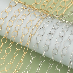 Golden and silver textured metal chains for DIY jewelry making displayed on a stand