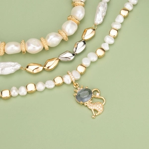 Baroque pearl necklaces with golden spacer beads and cat pendant on olive background