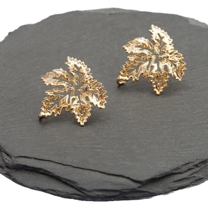 Detailed 18k gold-plated vintage leaf earrings on a natural dark grey stone base