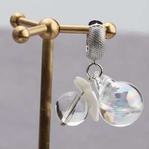 18k gold plated earring with clear glass ball and iridescent charm on a metal stand