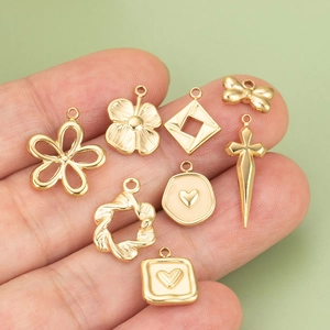 Main tenant des pendentifs dorés en acier 316L en forme de fleur et cœur pour bijoux DIY
