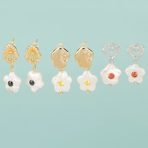 Trois paires de boucles d'oreilles perles et zircon coloré sur fond bleu clair