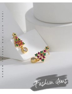 Gros plan sur des boucles d'oreilles sapin de Noël en or avec zircons rouges et verts vifs