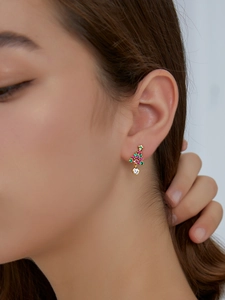 Gros plan d'une boucle d'oreille sapin de Noël avec zircons colorés portée par un mannequin