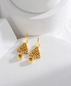 Détail des boucles d'oreilles sapin de Noël dorées avec cristaux sur pierre blanche