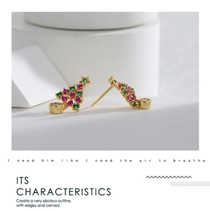 Détail de boucles d'oreilles sapin de Noël dorées avec zircons rouges et verts