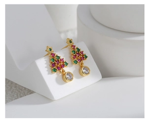 Détail de boucles d'oreilles sapin de Noël avec zircons rouges et verts sur métal doré