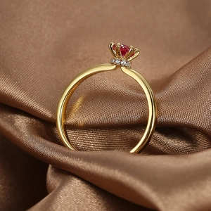 Luxurious gold-plated brass ring with crown-set red zircon on dark silk background