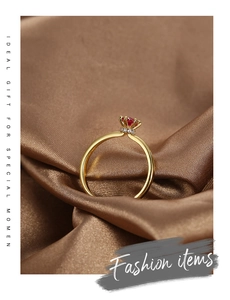 Detail of gold plated brass ring with red zircon stone and white diamond halo