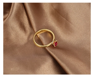 Macro shot of heart-shaped red zircon gold ring with surrounding white stones