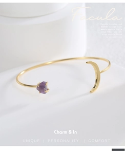 Makroansicht von goldenem Mond und rotem Amethyst auf einem offenen Armreif