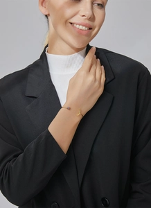 Detail eines eleganten Gold-Mond-Armreifs mit lila Cluster-Steinen am Handgelenk