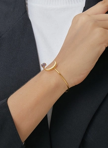 Eleganter vergoldeter Armreif mit Mondmotiv und lila Naturstein, am Handgelenk getragen