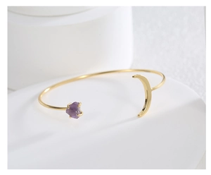 Detailaufnahme des vergoldeten Mond-Armreifs mit violettem Rohstein auf weißem Display