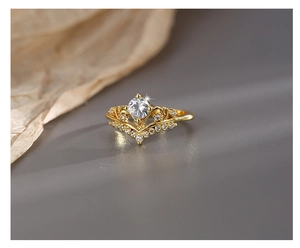Makroaufnahme des kronenförmigen vergoldeten Rings mit Zirkon und diamantbesetzter V-Form