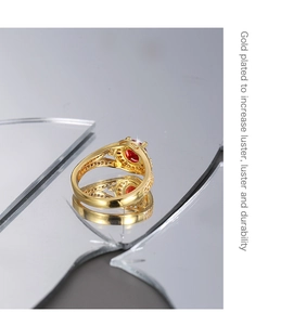 Vue macro d'une bague dorée avec zircon rouge et détails pavés sur un miroir brisé