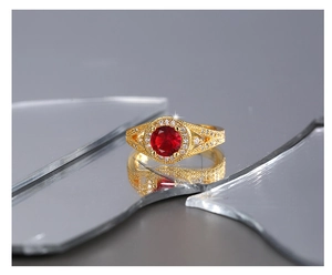 Gros plan d'une bague vintage dorée avec zircon rouge central et halo de diamants