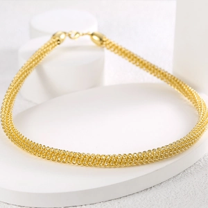 Minimalistisches goldenes Mesh-Halsband mit Karabinerverschluss auf weißem Podest