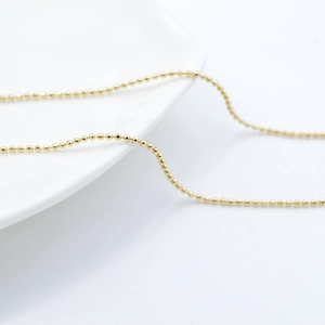 Collana a sfere placcata oro 18 carati su un elegante piatto in ceramica bianca