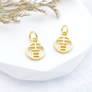 Golden round hollow charm with Chinese character 'Ji' on a minimalist stone display