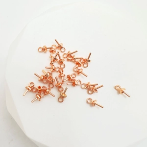 Bulk 18k rose gold plated eye pins with pearl cup bails on white stone display base